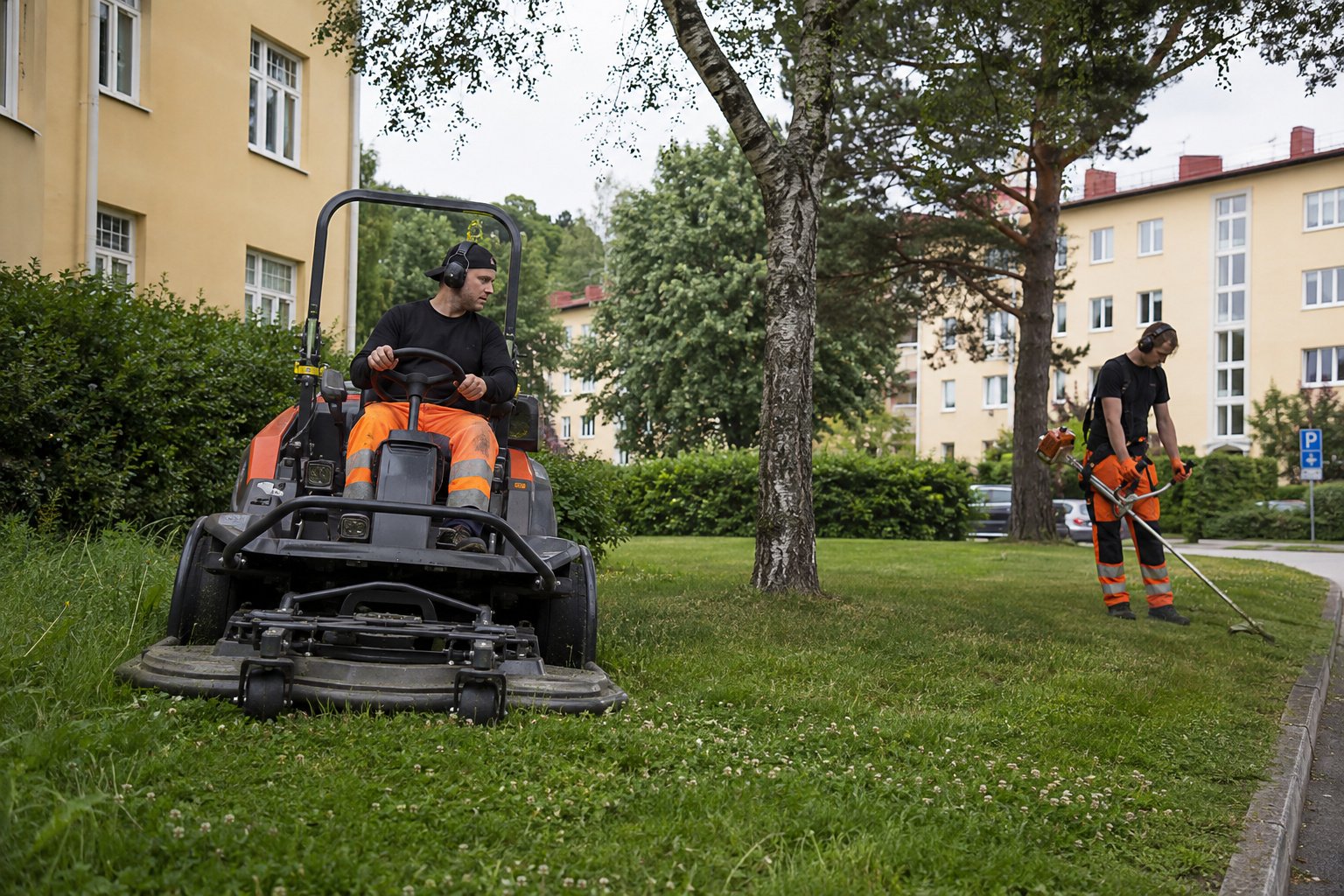 Fastighetsskötare klipper och trimmar gräs vid svenska bostadshus